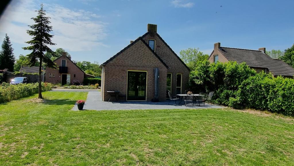 een stenen huis met een tafel in een tuin bij Vakantiewoning Maas en Waal 277 in Ewijk