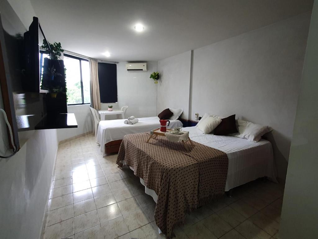 a hotel room with two beds and a flat screen tv at Flat mobiliado praia, João Pessoa PB PROMOÇÃO in Cabedelo