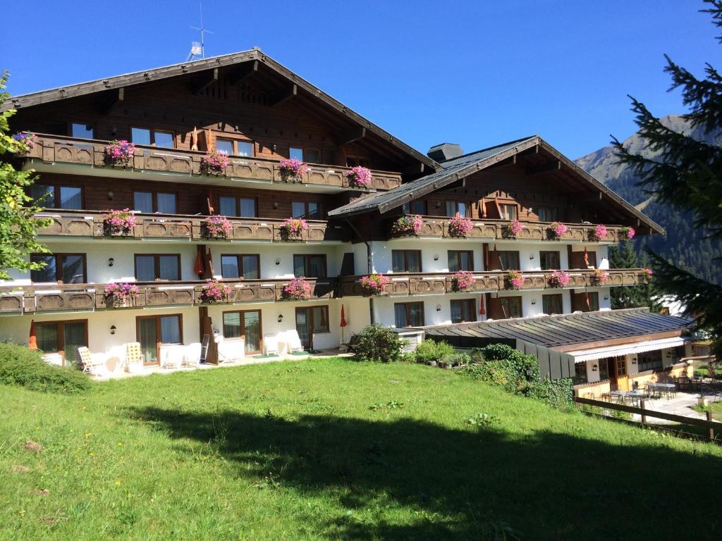 ein großes Gebäude mit Blumen auf den Balkonen in der Unterkunft Suitehotel Kleinwalsertal in Hirschegg