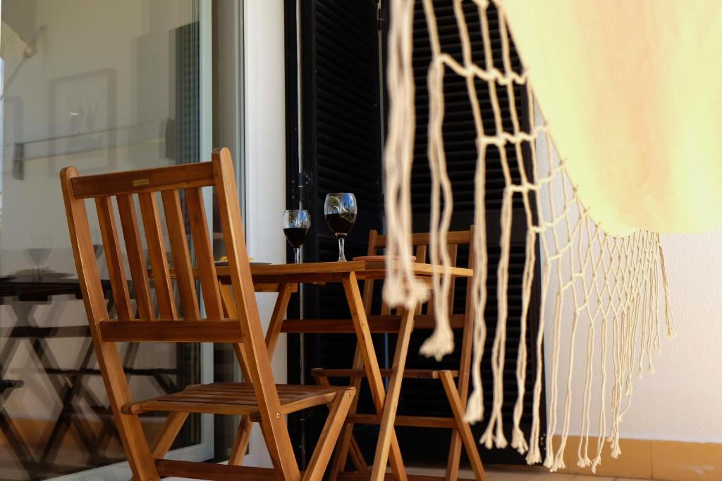 a wooden chair and a glass of wine in front of a window at Between Golf and Beach in Portimão