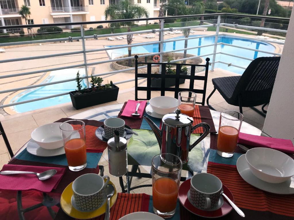 アルヴォルにあるSea and Pool at Vila da Praiaのプール付きのバルコニーにテーブルと食べ物プレートがあります。