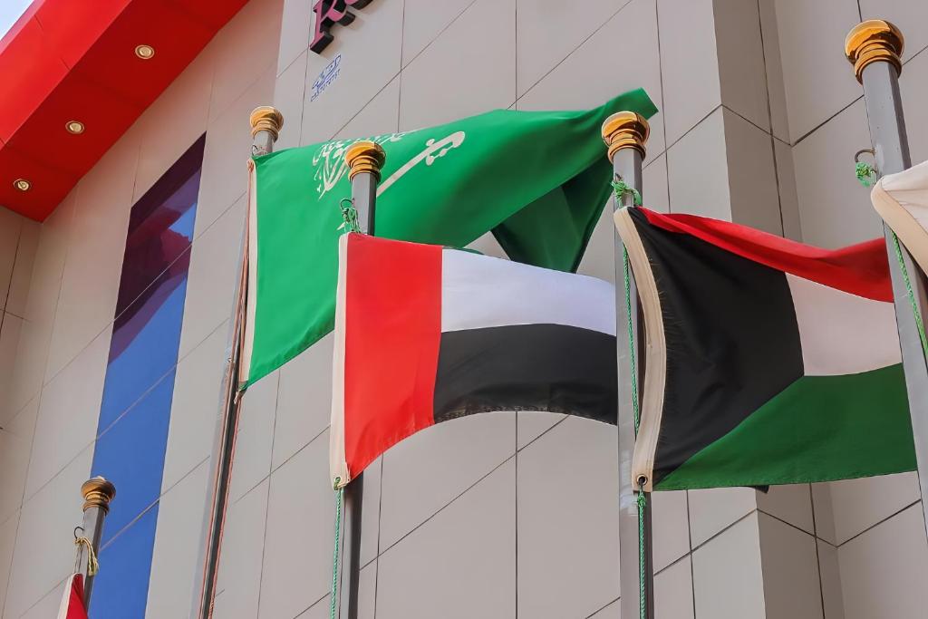 three flags flying in front of a building at Rose Park Riyadh in Riyadh