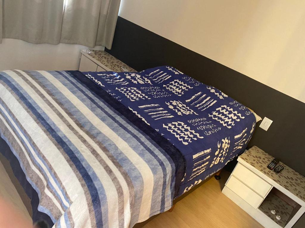 Una cama con una manta azul y blanca. en Wall Street Flat - Centro, en Caxias do Sul