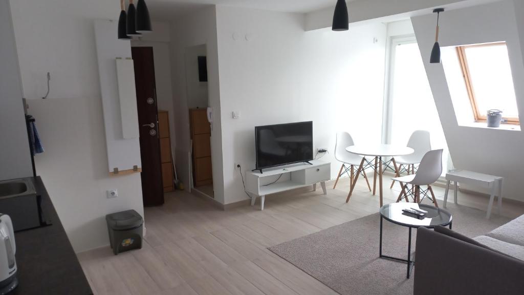 - un salon avec une télévision, une table et des chaises dans l'établissement Sunny apartment, à Skopje