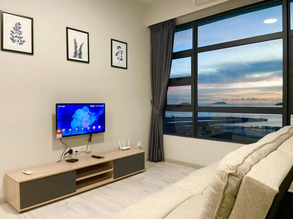 a living room with a tv and a large window at Sunset Seaview Vacation Condos @ Jesselton Quay in Kota Kinabalu