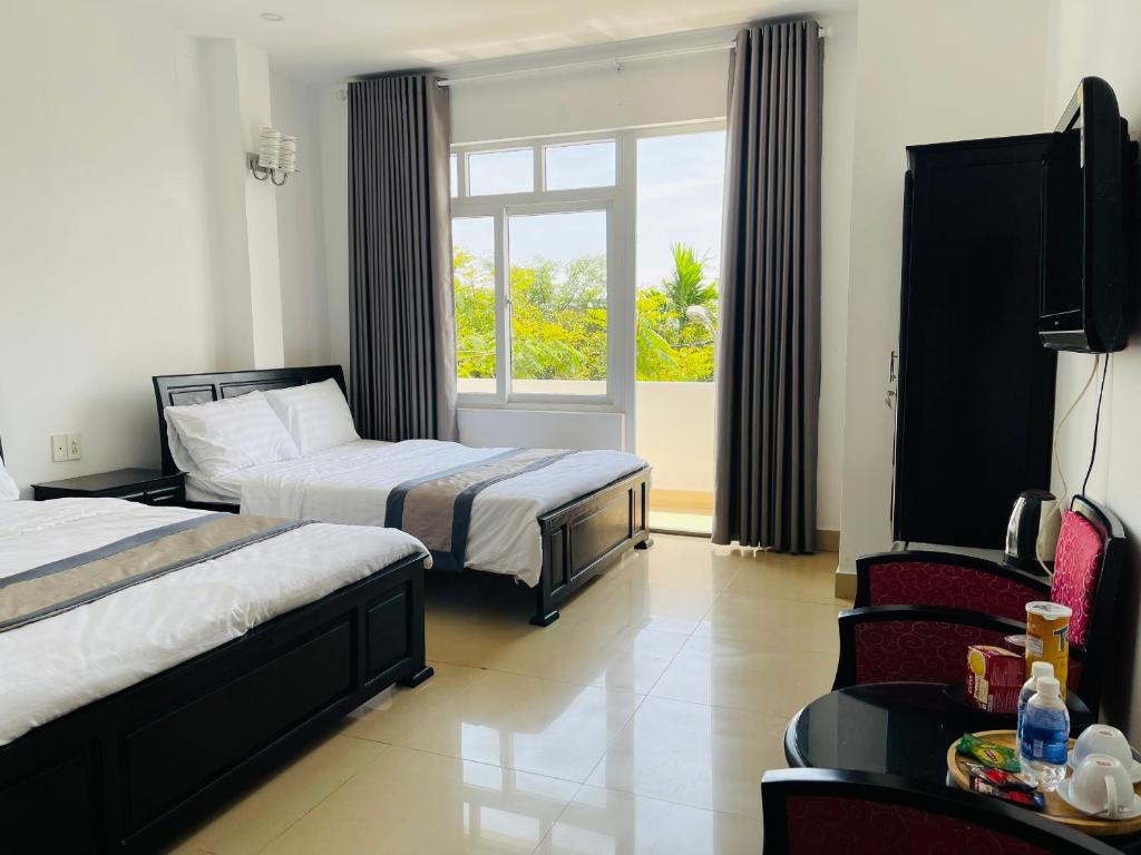una camera d'albergo con due letti e una finestra di THẢO AN 2 HOTEL Huế a Thôn Lại Thê