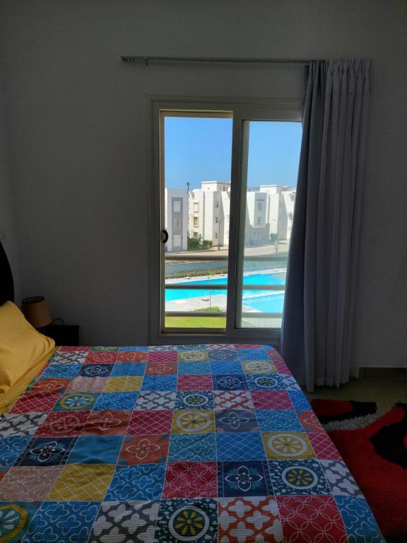 a bedroom with a quilt on a bed and a window at Amwaj North coast chalet families only in El Alamein
