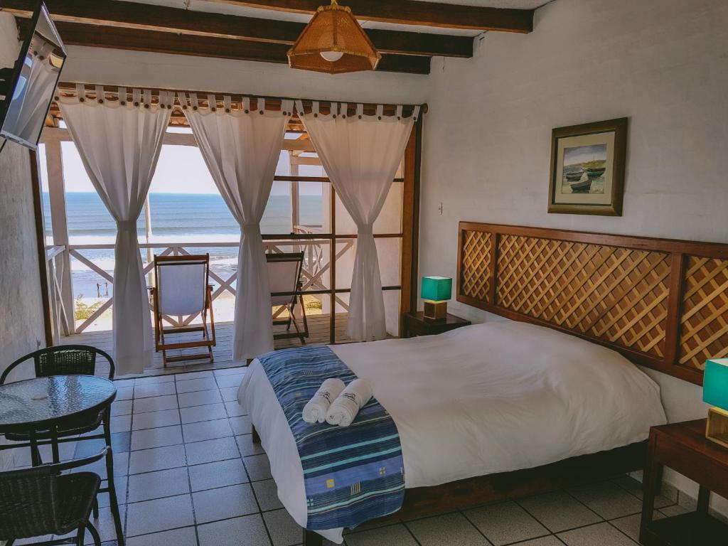 a bedroom with a bed and a view of the ocean at Delfines de Chicama Hotel in Puerto Chicama