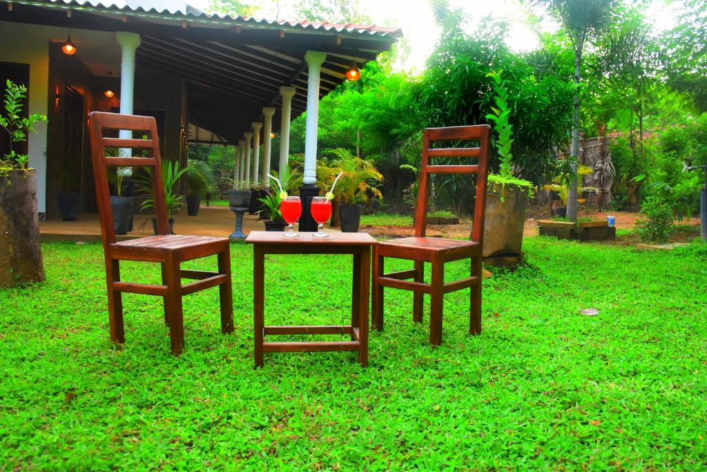 Dos sillas y una mesa con una vela. en Nature World Udawalawe, en Udawalawe