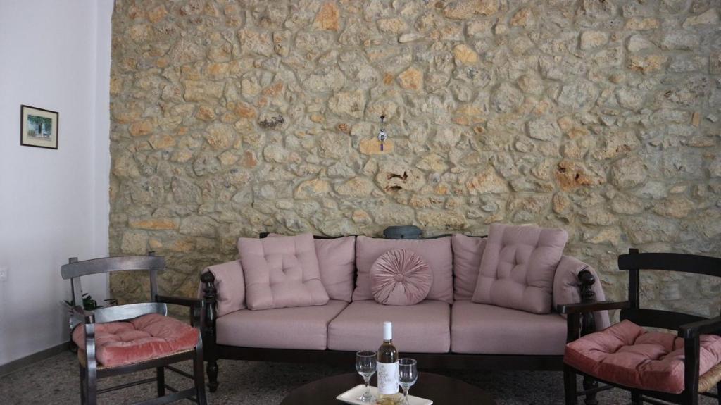 a couch sitting in front of a stone wall at Artemis House in Agios Nikolaos