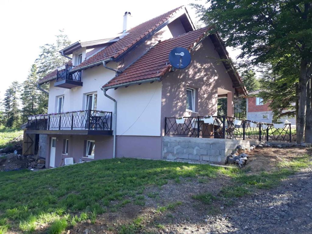 a small white house with a porch and a balcony at Vila Ljuti krš in Divčibare