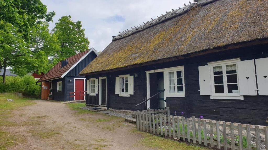 una antigua casa negra con techo de paja en Hästveda Vandrarhem och Stugor en Hästveda