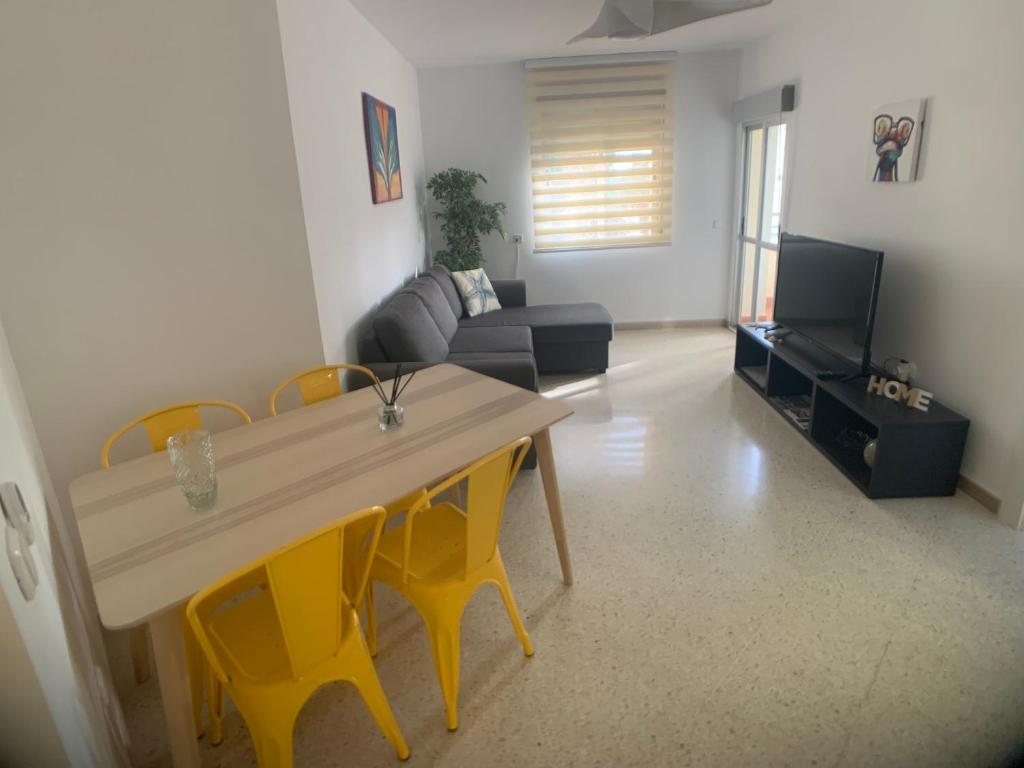 a living room with a table and yellow chairs at Motril - Poniente Beach in Motril