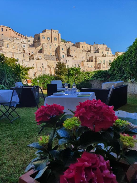 Il Giardino di Eleonora في ماتيرا: طاولة مع الزهور الحمراء أمام المبنى