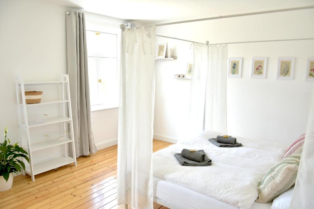 a white bed in a room with a window at frigg flats I Scandi InteriorI JugendstilI Altbau in Landshut