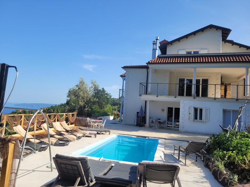 a villa with a swimming pool in front of a house at Ferienwohnung mit Pool Kroatien mit Meerblick und Pool in Lovran