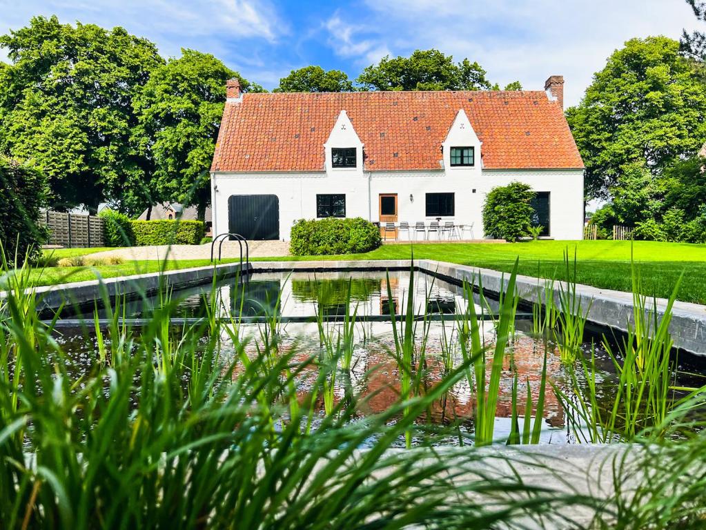 una casa con un estanque delante de ella en Weynhoven en Brecht