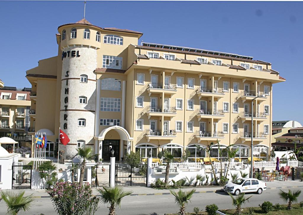 een groot gebouw met een auto voor de deur bij Hotel Sinatra in Kemer