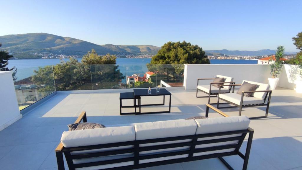 a patio with chairs and a table and a view of the water at High View House in Okrug Donji