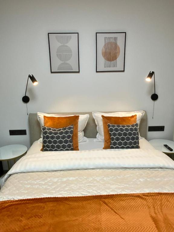 a bedroom with a large bed with two lamps at Alėjos Apartmentai City in Druskininkai