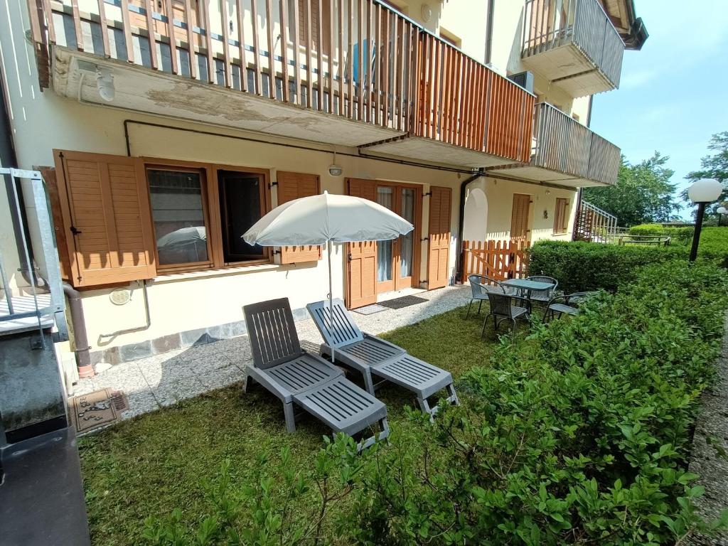 zwei Stühle und ein Regenschirm im Hof eines Gebäudes in der Unterkunft Maison Gregory in Prada