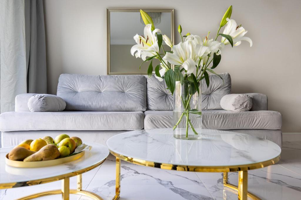 a living room with a couch and a table with a vase of flowers at MIRA APARTMENTS in Gdańsk