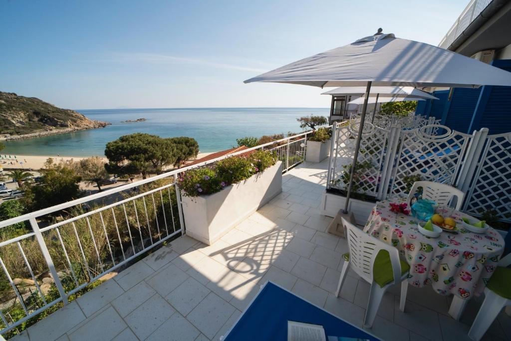 a balcony with a table and an umbrella and the ocean at Le sirene in Seccheto
