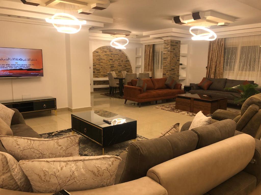 una gran sala de estar con sofás y TV. en Ghena en El Cairo