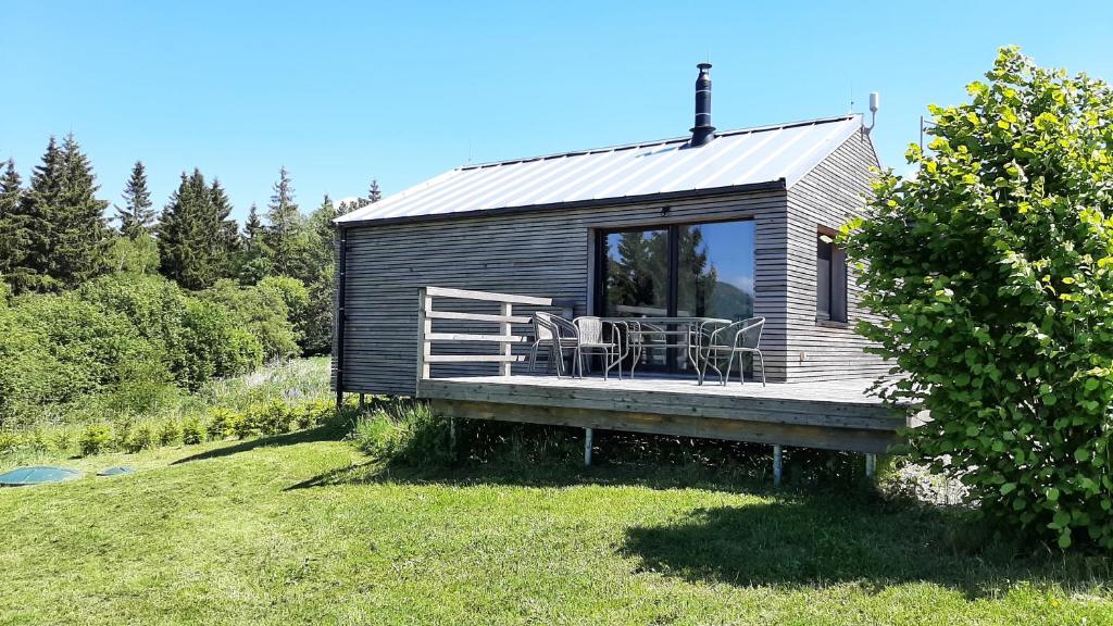 eine kleine Hütte mit einer Terrasse im Gras in der Unterkunft Chata Lesní in Klíny