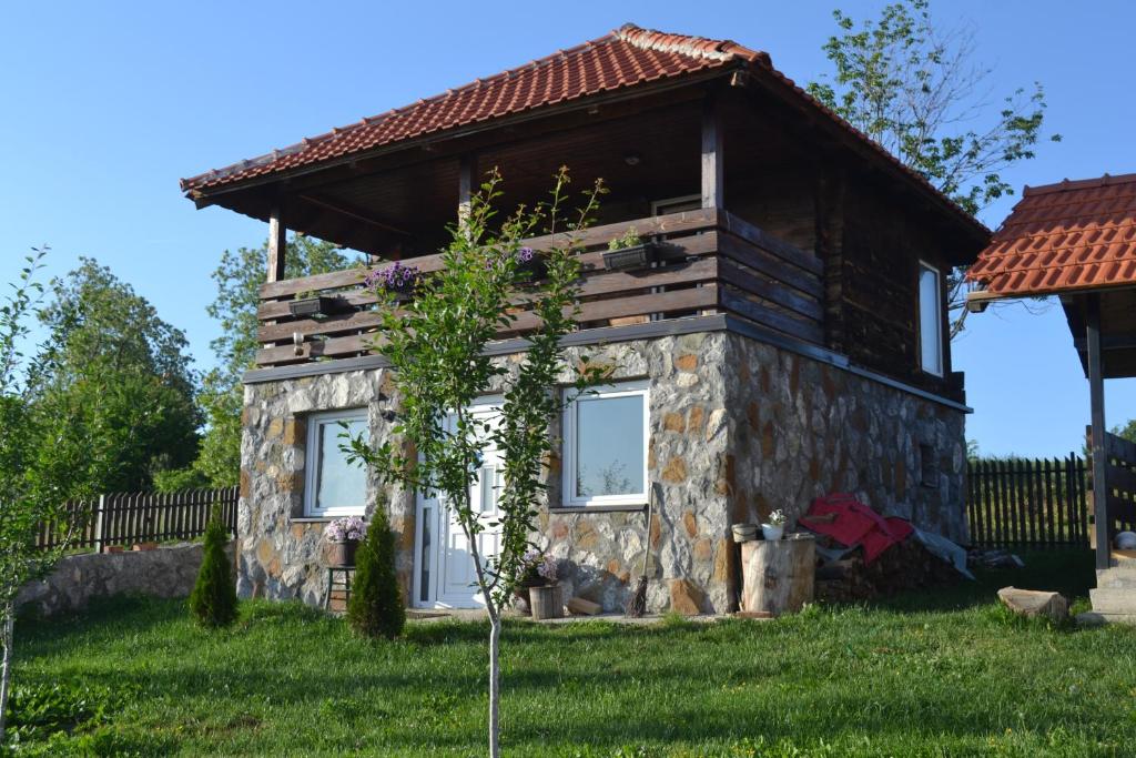 une petite maison en pierre avec un arbre en face de celle-ci dans l'établissement Zlatibor Cottages, à Zlatibor