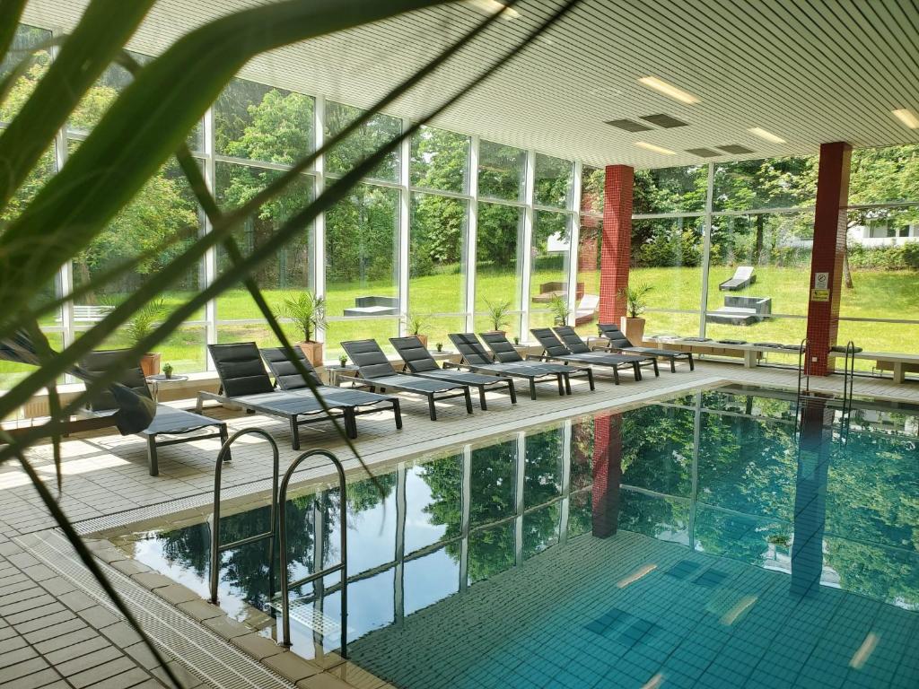 einen Pool mit Liegestühlen neben einem Gebäude in der Unterkunft CAREA Residenz Hotel Harzhöhe in Hahnenklee-Bockswiese