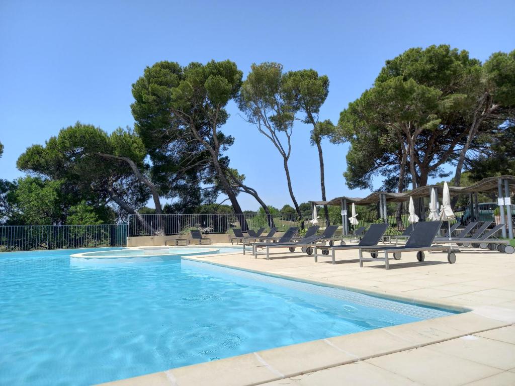 a swimming pool with lounge chairs and trees at Appartement cosy pour un séjour bien-être in Saumane-de-Vaucluse