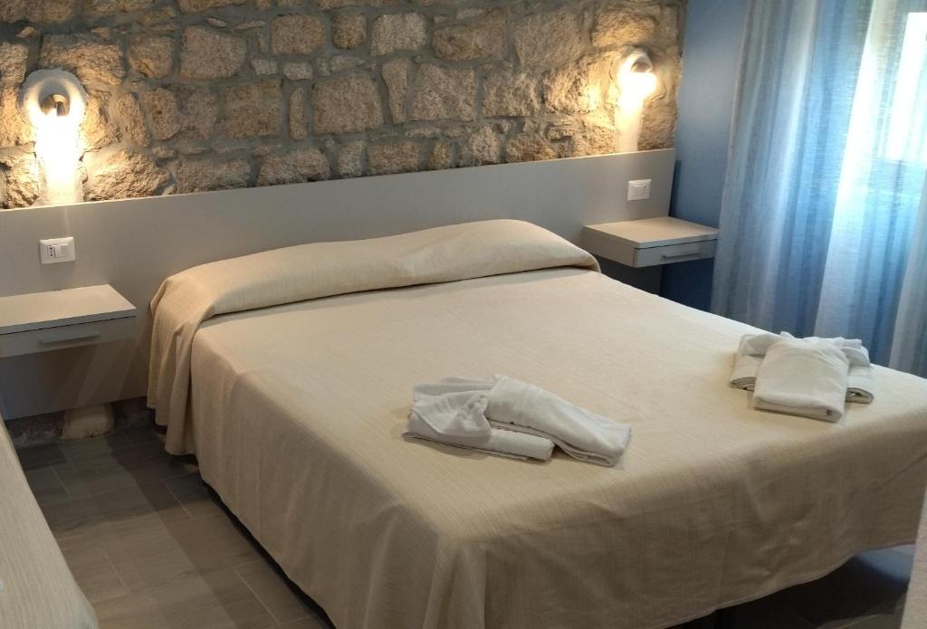a bedroom with a bed with towels on it at Lungomare Bed rooms in Santa Maria Navarrese