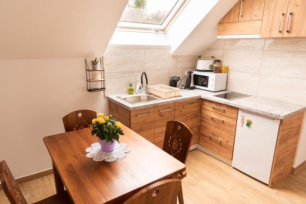 una cocina con una mesa de madera con un jarrón de flores. en Apartamenty Home&Spa en Rabka