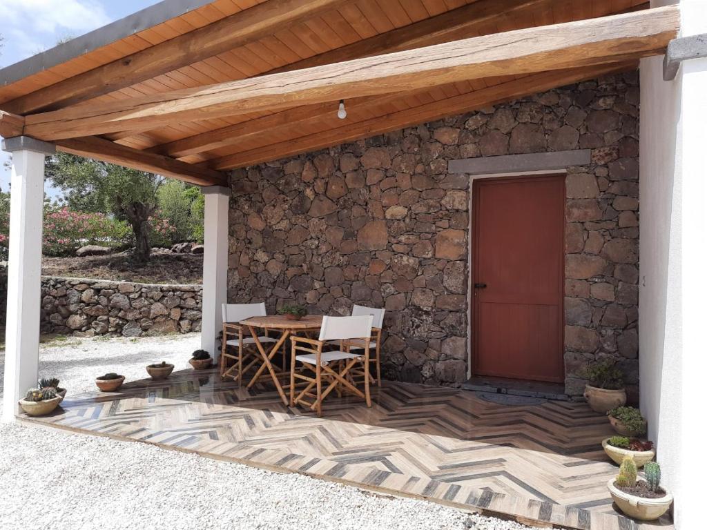 un patio con tavolo, sedie e parete in pietra di Casa Olivastra a Dorgali