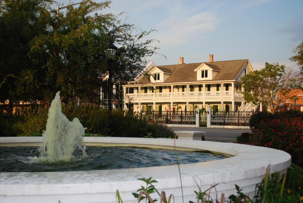 a fountain in front of a large white house at The Hotel Magnolia in Foley