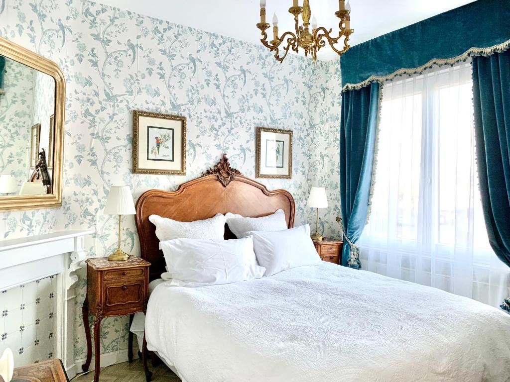 ein Schlafzimmer mit einem Bett mit blauen und weißen Tapeten in der Unterkunft Maison Trianon 1928 in Quiévrechain