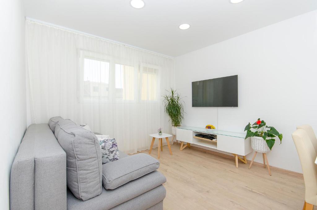 a white living room with a couch and a tv at Lanuna apartment in Split