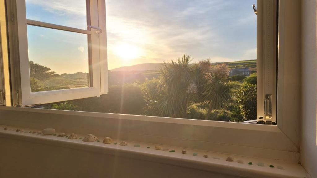 a window with a view of the sunset at Cosy terraced Cornish cottage near the sea in Penzance