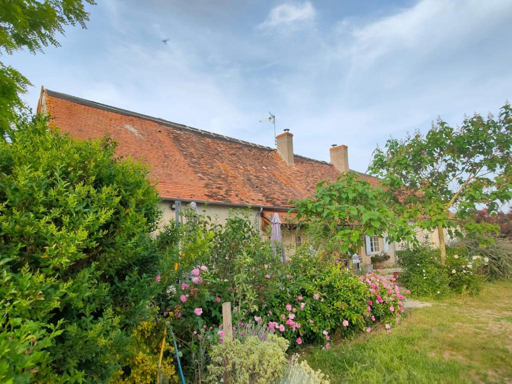 une ancienne maison avec un toit rouge et quelques fleurs dans l'établissement Gite de la Maison Fort, à Vereaux