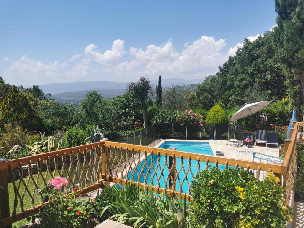 a swimming pool in a garden with a wooden fence at Guest House Casa Cassien in Montauroux