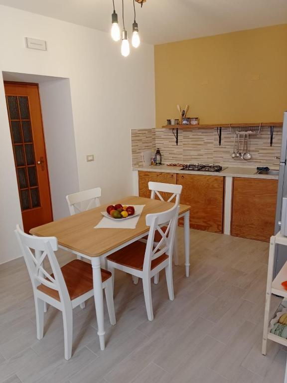 a kitchen with a wooden table with chairs and a bowl of fruit at In Centro - Noto in Noto