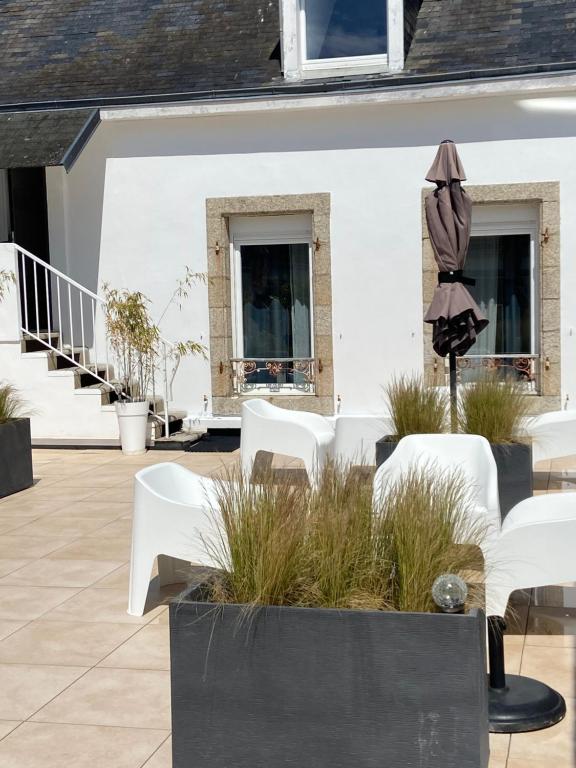eine Terrasse mit weißen Stühlen und einem Sonnenschirm in der Unterkunft LA VILLE A LA MER N°3 in Concarneau