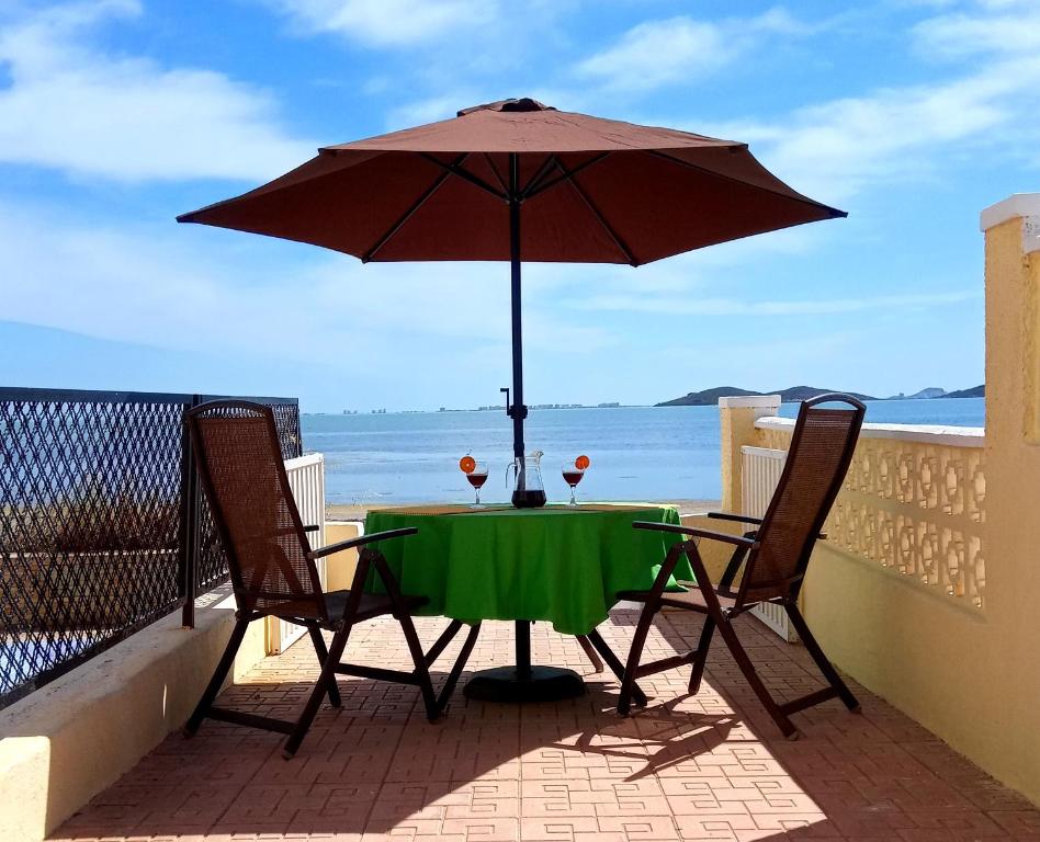 un tavolo e due sedie con ombrellone su un balcone di Beachfront House sea views near historic Cartagena a Cartagena