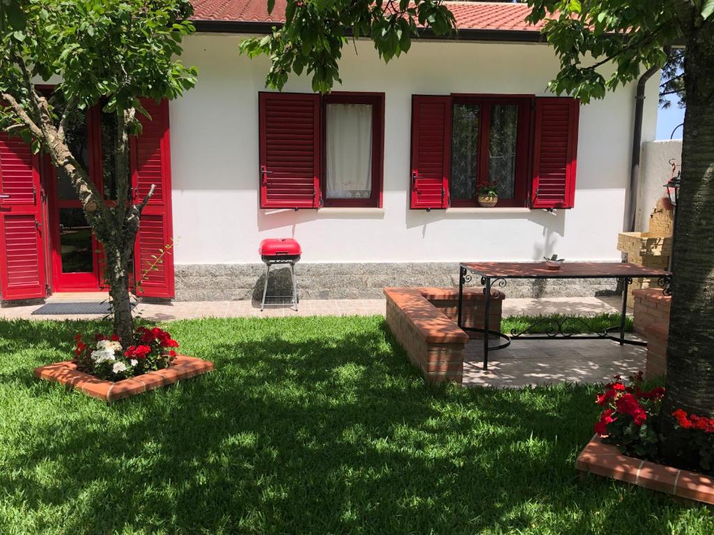 a house with red shutters and a table in the yard at La Casa delle Ortensie Guest House in Scilla