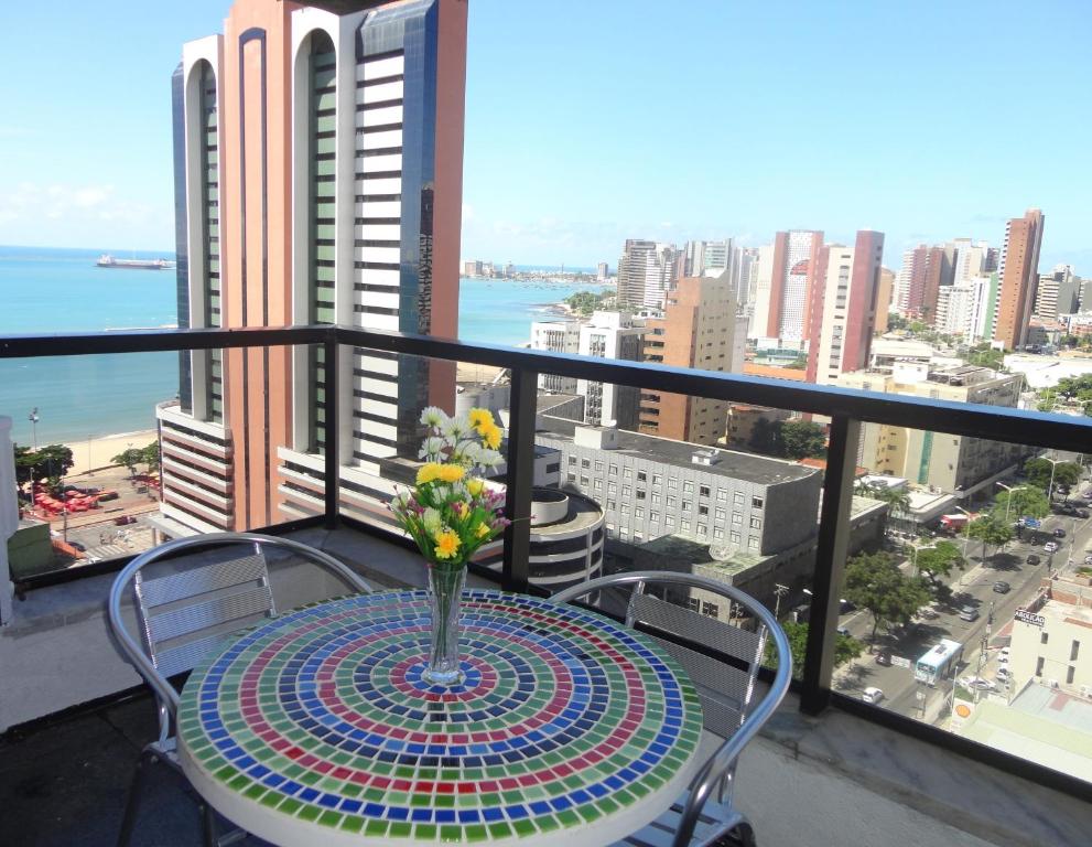 una mesa con un jarrón de flores en el balcón en Via Venetto - Vista Mar, en Fortaleza