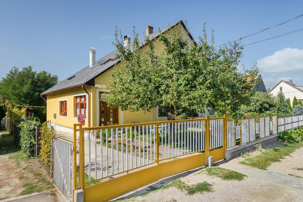 a yellow fence in front of a yellow house at Katica Apartment in Balatonszárszó