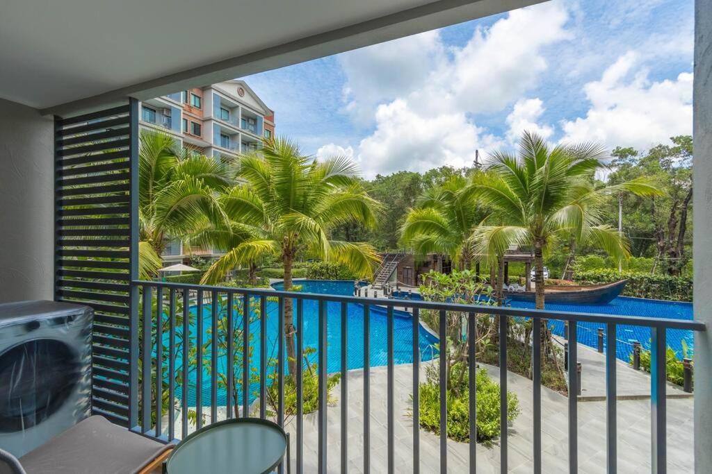 a balcony with a view of a pool and palm trees at Title Naiyang residence Excellent location with pool view in Nai Yang Beach