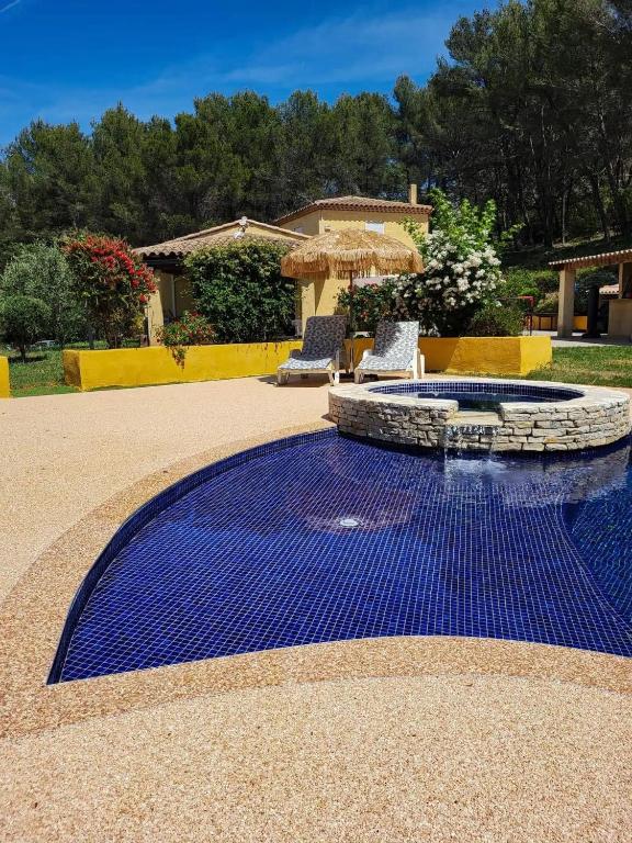 une piscine avec un sol en carrelage bleu et deux chaises dans l'établissement L'Eden sous l'olivier, à Auriol
