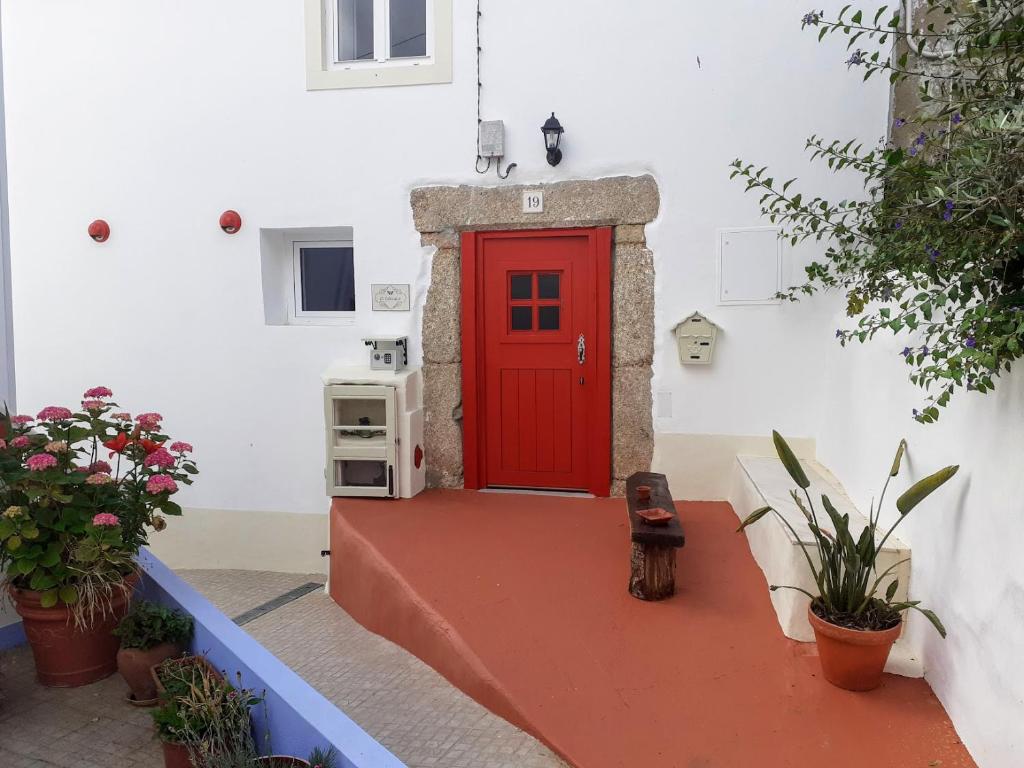 a red door in a white building with plants at O Casulo in Marvão